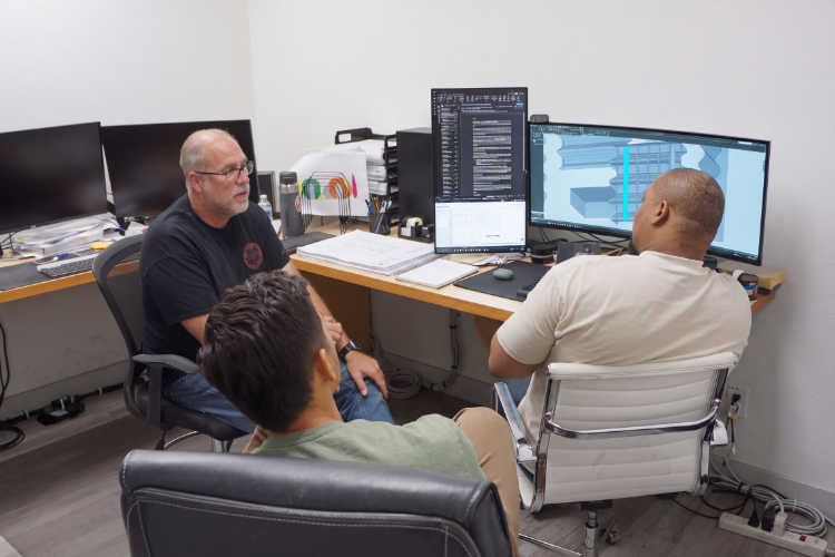 Engineers and programmers collaborating on CNC programming and project planning for fabrication projects.